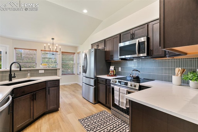 kitchen with dark brown cabinetry, appliances with stainless steel finishes, lofted ceiling, decorative light fixtures, and sink