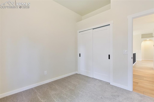 unfurnished bedroom featuring a closet and light colored carpet