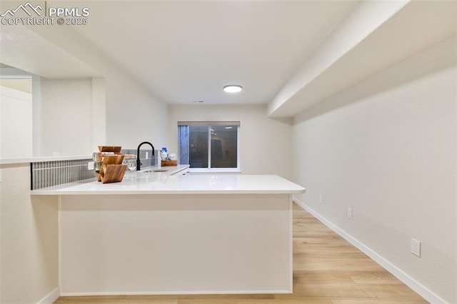 kitchen featuring light hardwood / wood-style floors, sink, and kitchen peninsula