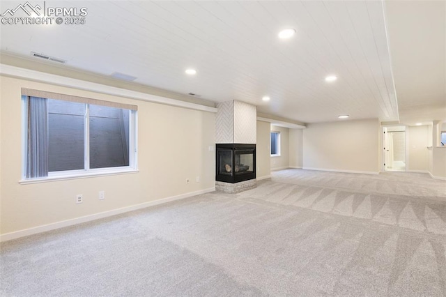 unfurnished living room featuring light carpet and a multi sided fireplace