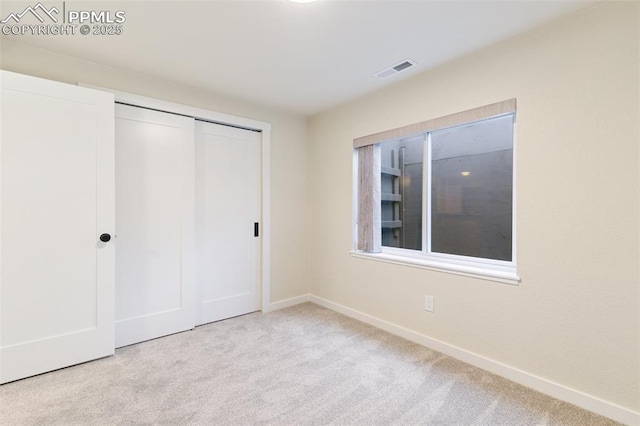 unfurnished bedroom with a closet and light colored carpet