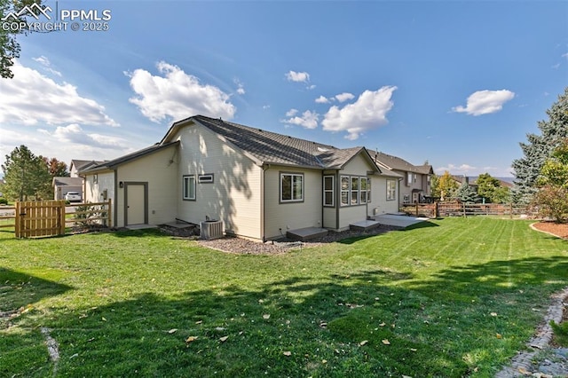 rear view of property with central AC unit, a patio, and a yard