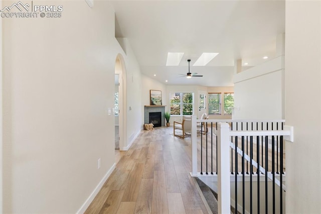 corridor with light wood-type flooring and vaulted ceiling with skylight