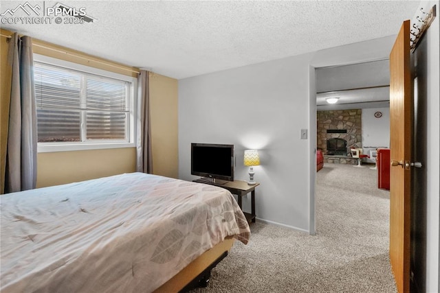 bedroom featuring light carpet, a stone fireplace, and a textured ceiling