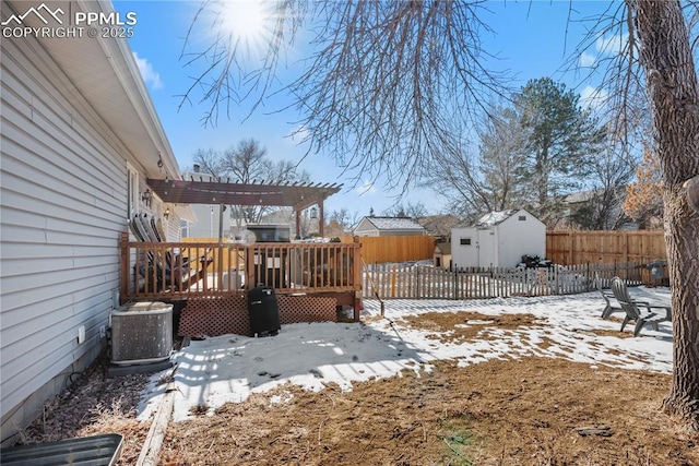 yard layered in snow with central AC unit, a pergola, a deck, and a storage unit