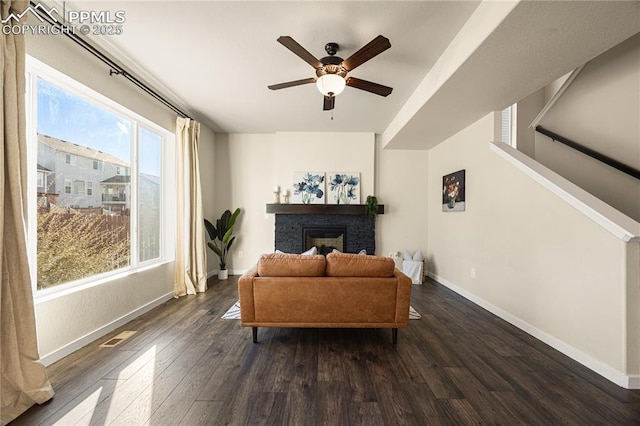 living room with a brick fireplace, dark hardwood / wood-style flooring, and ceiling fan