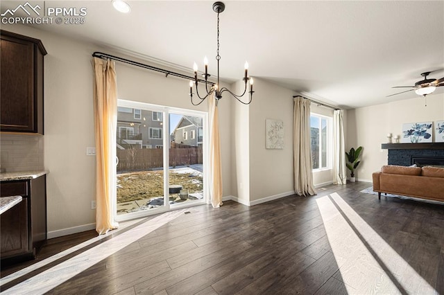 dining space with ceiling fan with notable chandelier and dark hardwood / wood-style flooring