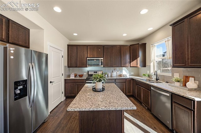 kitchen with light stone counters, dark brown cabinetry, stainless steel appliances, and a kitchen island