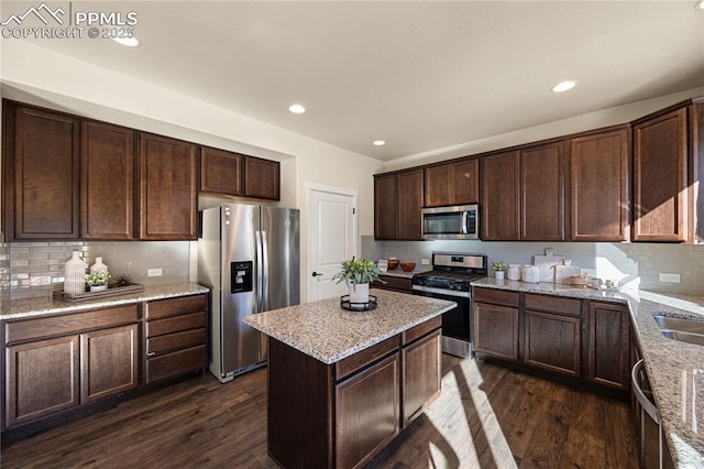 kitchen with light stone countertops, dark brown cabinetry, a center island, dark hardwood / wood-style flooring, and stainless steel appliances