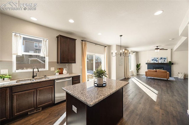 kitchen with decorative backsplash, a kitchen island, stainless steel dishwasher, light stone counters, and sink