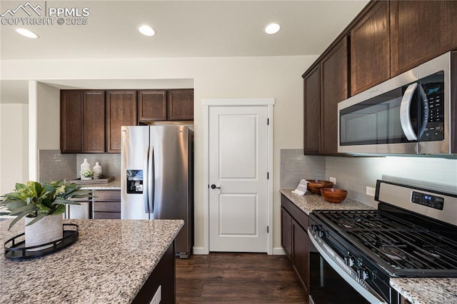 kitchen featuring light stone counters, stainless steel appliances, and dark brown cabinetry