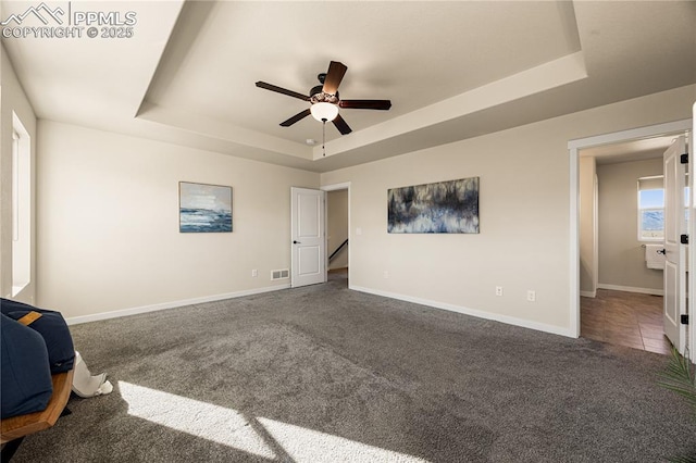 carpeted bedroom featuring ceiling fan and a raised ceiling