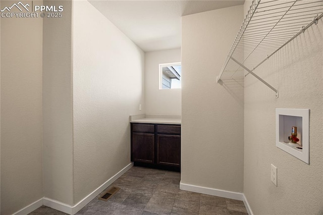 clothes washing area featuring hookup for a washing machine and cabinets