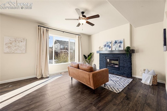 living room with ceiling fan, dark wood-type flooring, and a stone fireplace