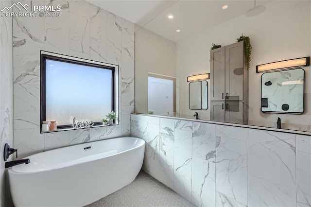 bathroom with tile patterned flooring, a bathtub, and tile walls