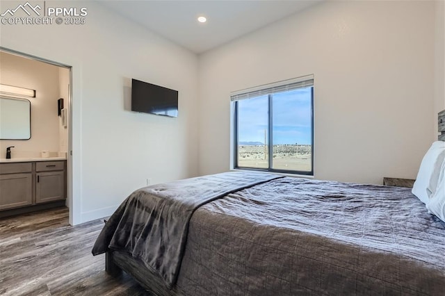 bedroom featuring connected bathroom, hardwood / wood-style flooring, and sink