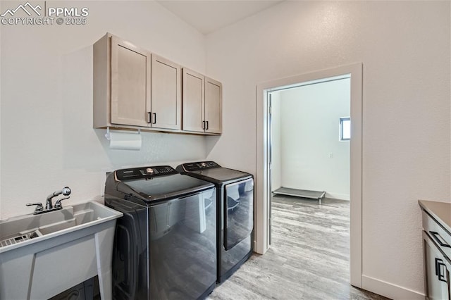 washroom featuring separate washer and dryer, sink, light hardwood / wood-style flooring, and cabinets