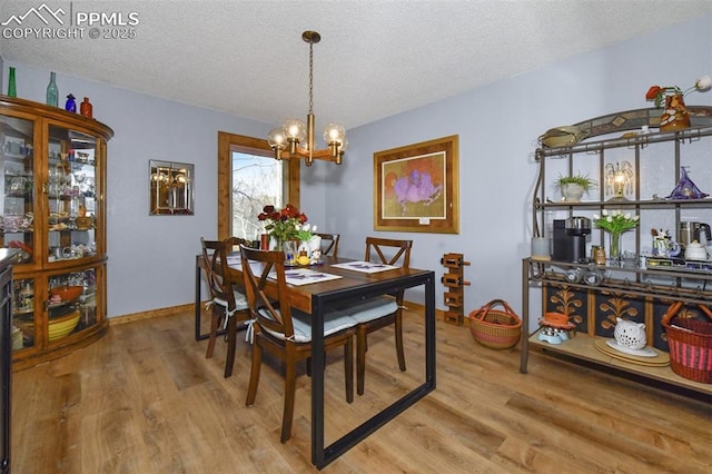 dining room featuring a notable chandelier, a textured ceiling, and light hardwood / wood-style floors