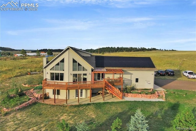 rear view of property with a wooden deck, a patio, and a lawn