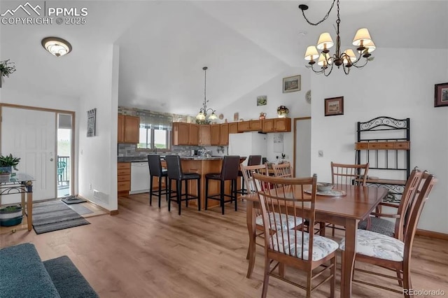 dining room with a notable chandelier, light hardwood / wood-style flooring, and high vaulted ceiling