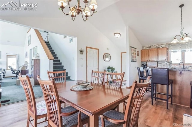 dining room featuring lofted ceiling, light hardwood / wood-style flooring, an inviting chandelier, and plenty of natural light