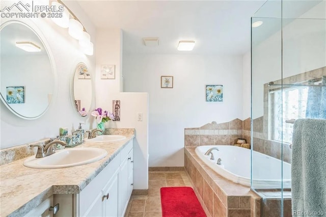 bathroom featuring tile patterned flooring, vanity, and tiled bath