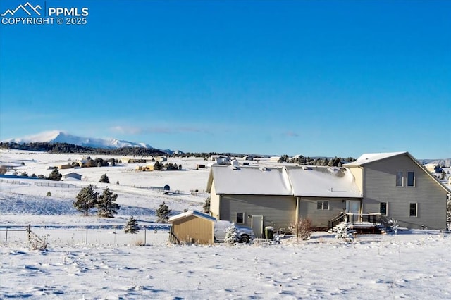 snow covered house featuring a storage unit and a mountain view