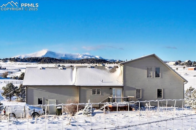 snow covered back of property featuring a mountain view