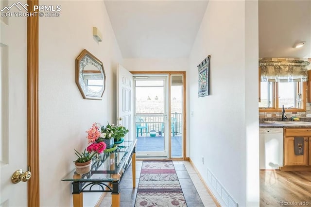 entryway with sink, vaulted ceiling, and light tile patterned flooring