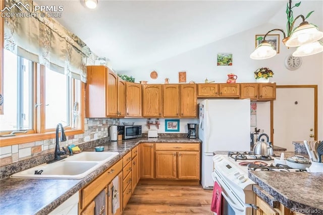 kitchen with lofted ceiling, sink, hardwood / wood-style flooring, white appliances, and decorative backsplash