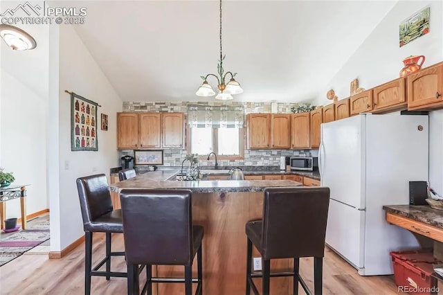 kitchen featuring white refrigerator, lofted ceiling, and a kitchen bar