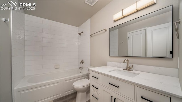 full bathroom featuring toilet, tiled shower / bath, and vanity