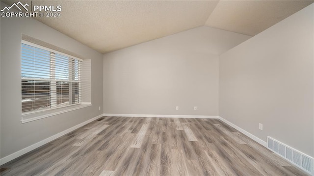 unfurnished room featuring light hardwood / wood-style floors and lofted ceiling