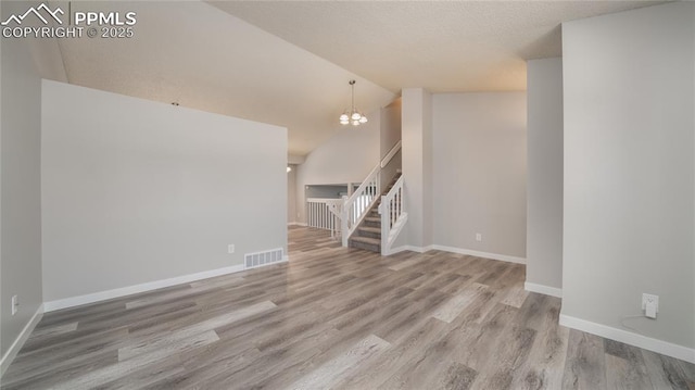 unfurnished living room with vaulted ceiling, a chandelier, and hardwood / wood-style flooring