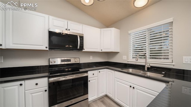 kitchen featuring vaulted ceiling, light hardwood / wood-style floors, sink, stainless steel appliances, and white cabinets