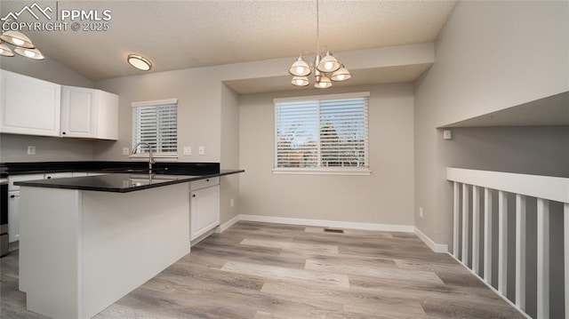 kitchen with a notable chandelier, pendant lighting, kitchen peninsula, sink, and white cabinetry