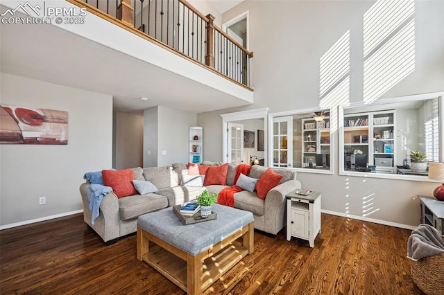 living room featuring dark wood-type flooring and a high ceiling