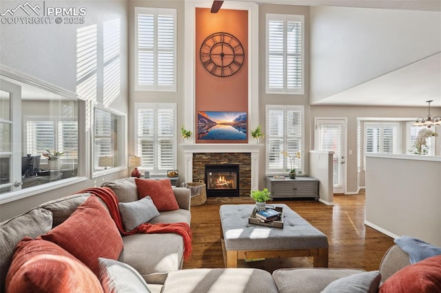 living room with a high ceiling, dark hardwood / wood-style flooring, an inviting chandelier, and a fireplace