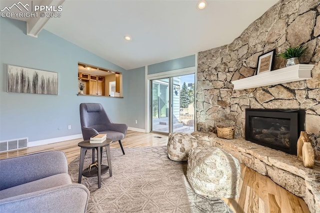 living room with light wood-type flooring, lofted ceiling with beams, and a fireplace