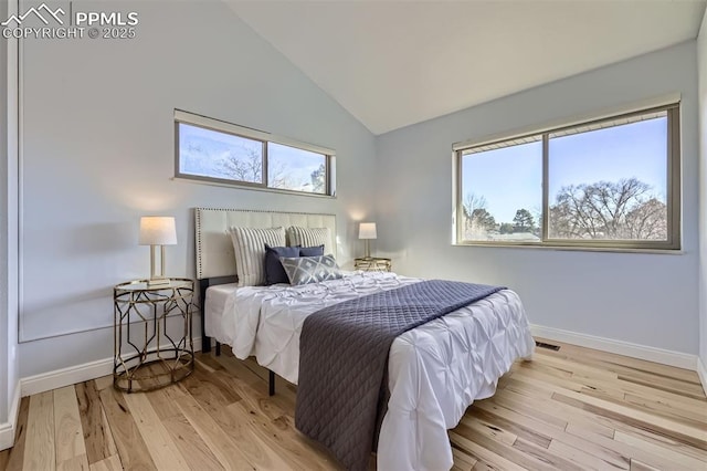 bedroom featuring high vaulted ceiling, multiple windows, and light hardwood / wood-style flooring