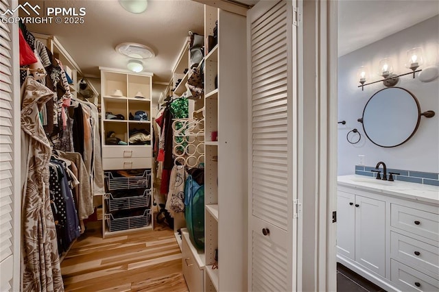 spacious closet with light hardwood / wood-style flooring and sink