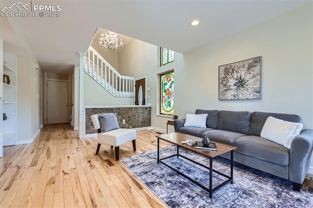 living room featuring hardwood / wood-style flooring, built in features, a notable chandelier, and a healthy amount of sunlight