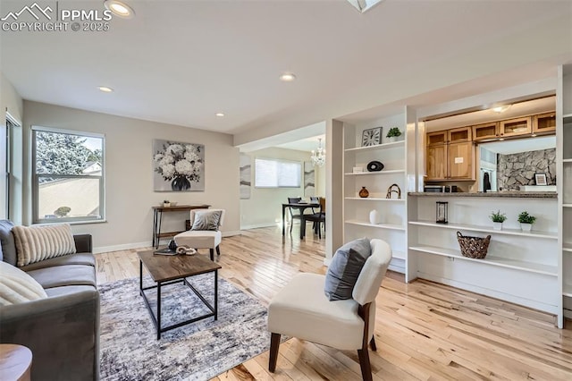 living room featuring built in features, a notable chandelier, and light wood-type flooring