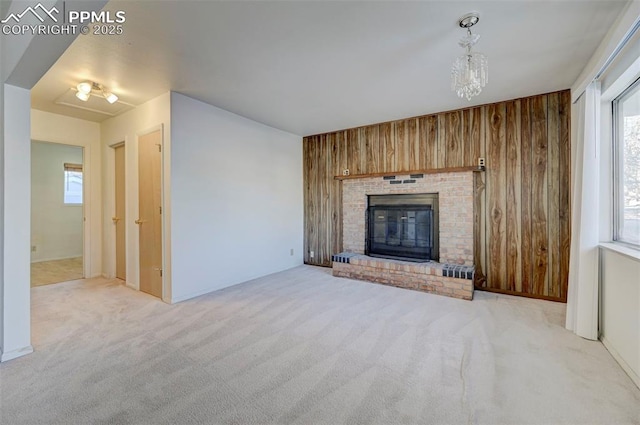 unfurnished living room with light colored carpet, a brick fireplace, and wooden walls