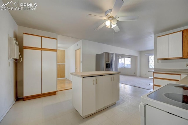 kitchen with stainless steel refrigerator with ice dispenser, white cabinetry, a center island, and white electric range oven