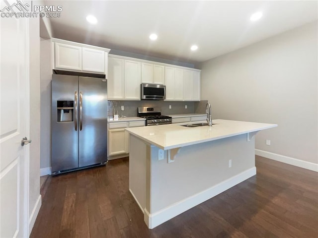 kitchen featuring an island with sink, stainless steel appliances, dark hardwood / wood-style floors, white cabinets, and sink