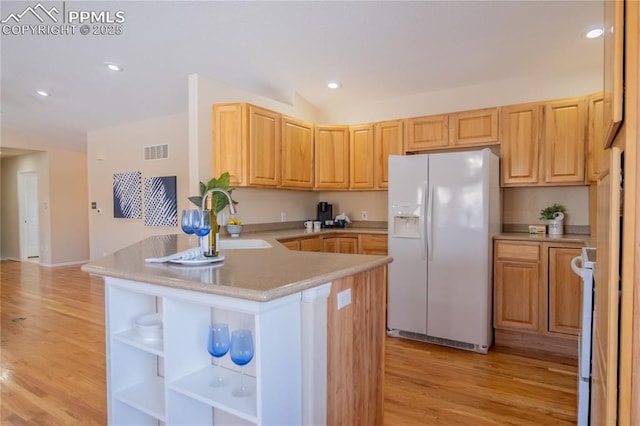 kitchen featuring white refrigerator with ice dispenser, light brown cabinetry, kitchen peninsula, light hardwood / wood-style flooring, and stove