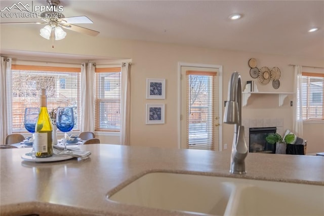 kitchen with ceiling fan, sink, and a fireplace