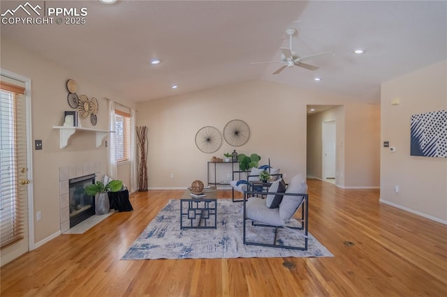 living room with ceiling fan, lofted ceiling, light hardwood / wood-style flooring, and a tile fireplace