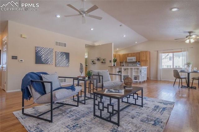 living room with ceiling fan, lofted ceiling, and light hardwood / wood-style flooring